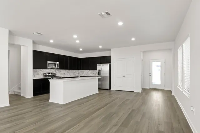 a kitchen with stainless steel appliances kitchen island wooden floors and white cabinets