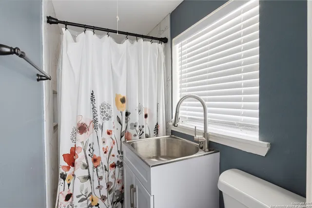 a bathroom with a granite countertop sink a mirror a window and a shower