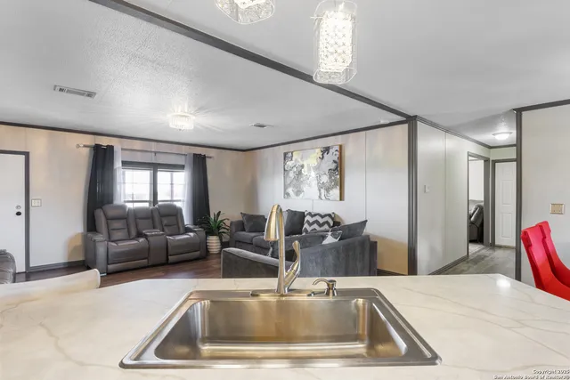 a kitchen with a sink and couches with wooden floor