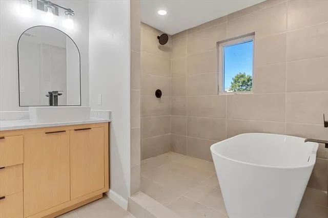 a bathroom with a granite countertop sink a mirror a bathtub and shower