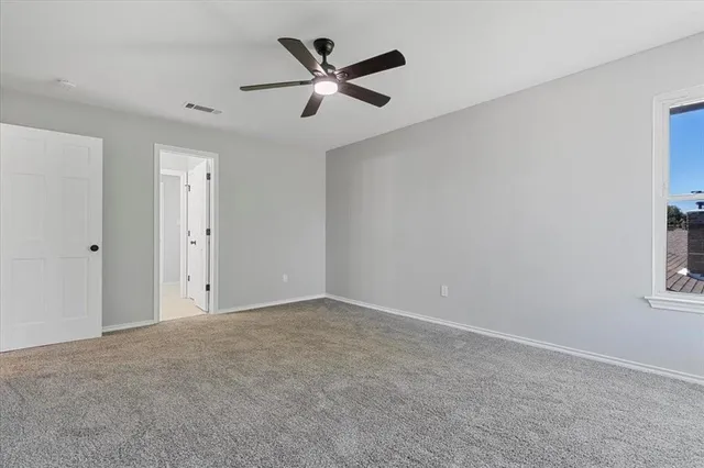 an empty room with windows and fan