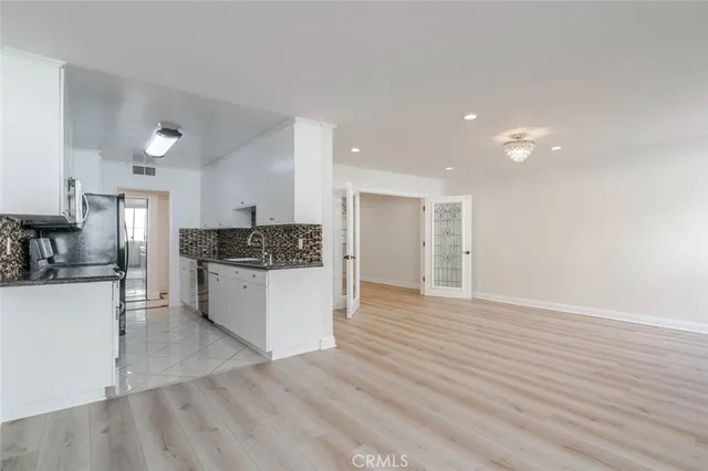 a view of kitchen with kitchen island wooden floors and stainless steel appliances