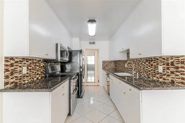 a kitchen with stainless steel appliances kitchen island granite countertop a sink stove and refrigerator