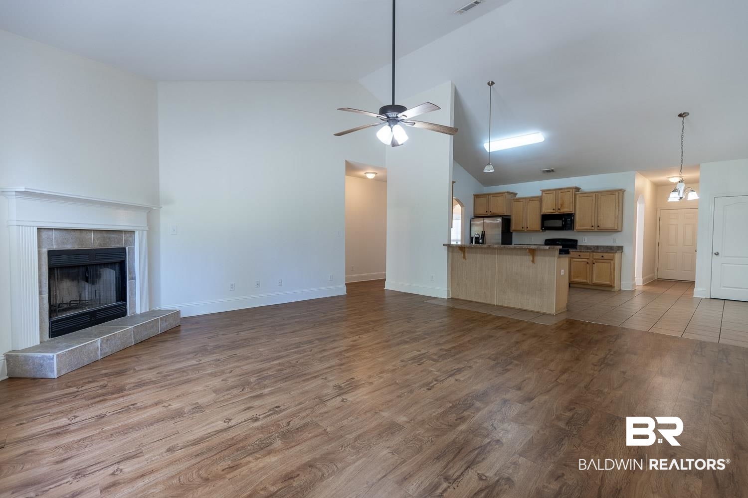 101 Normandy Street Fairhope, AL 36532 - Photo 9 of 18 Unfurnished living room featuring high vaulted ceiling, dark wood-type flooring, a tile fireplace, and ceiling fan