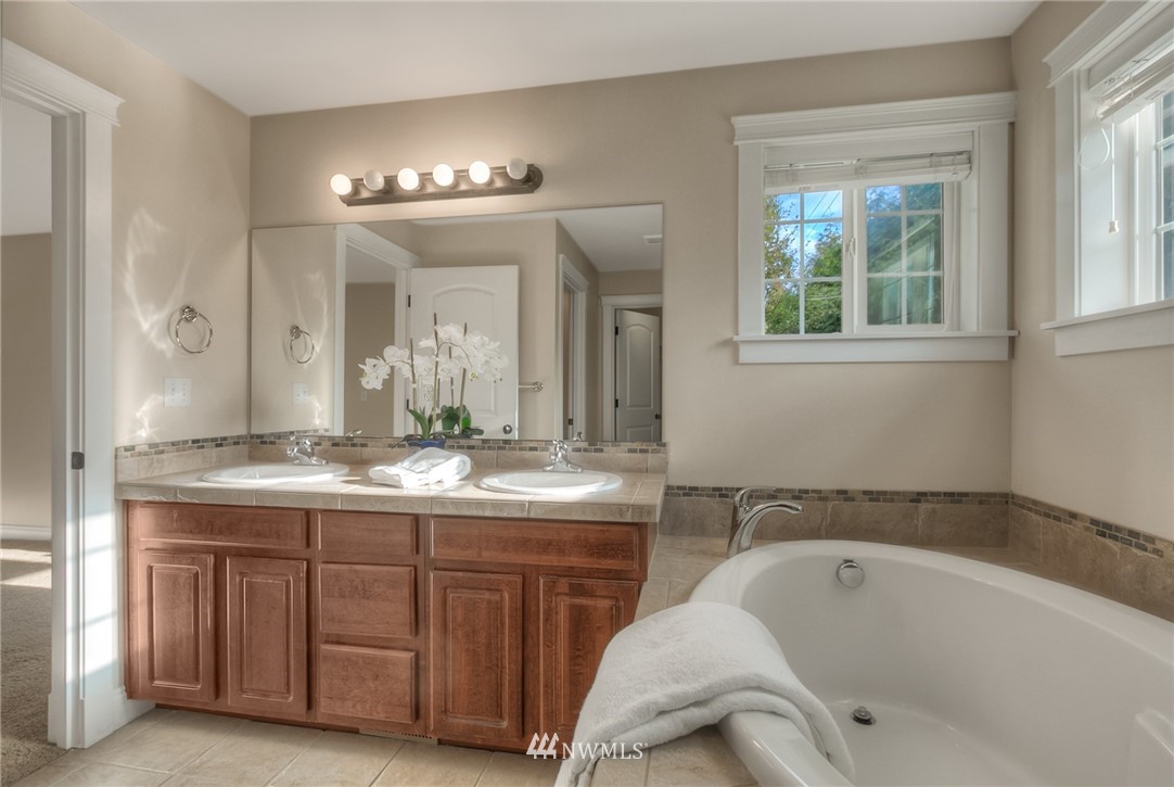 902 225th Place Southeast Bothell, WA 98021 - Photo 17 of 20 a bathroom with a tub a double vanity sink and a large mirror
