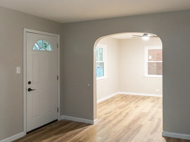 an empty room with wooden floor mirror and windows
