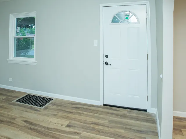 a view of an empty room with window and wooden floor