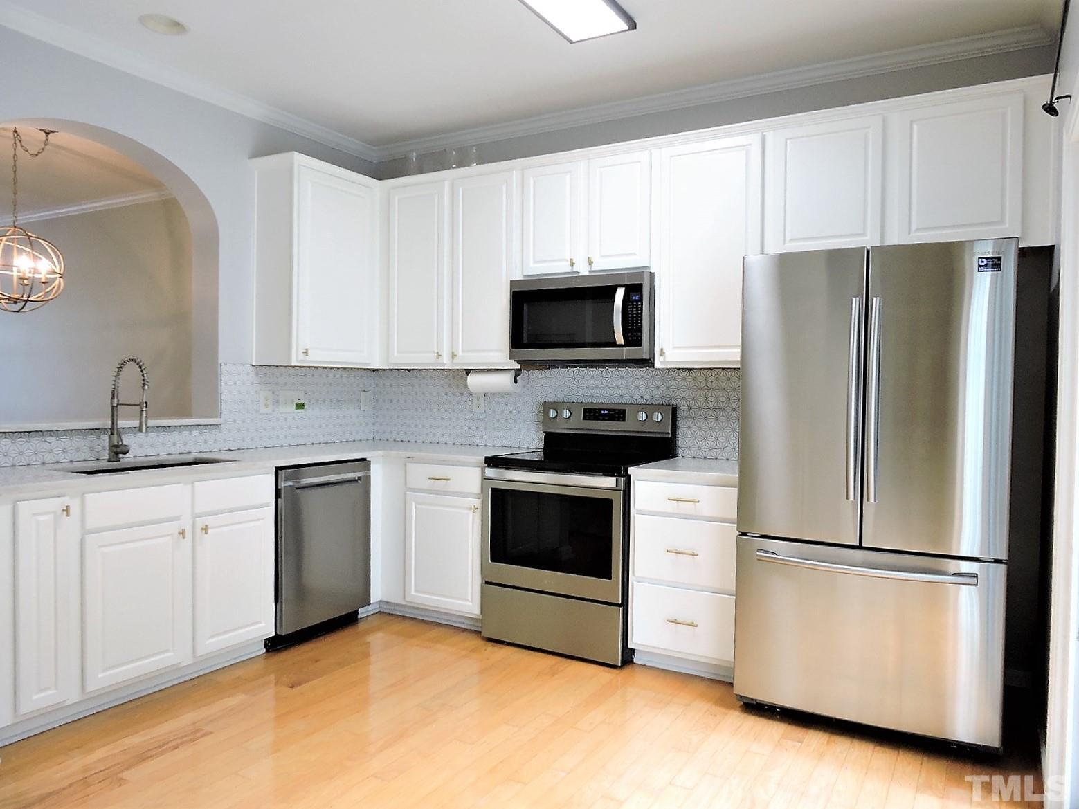 3811 Ramblewood Avenue Durham, NC 27713 - Photo 16 of 29 a kitchen with stainless steel appliances white cabinets and a refrigerator