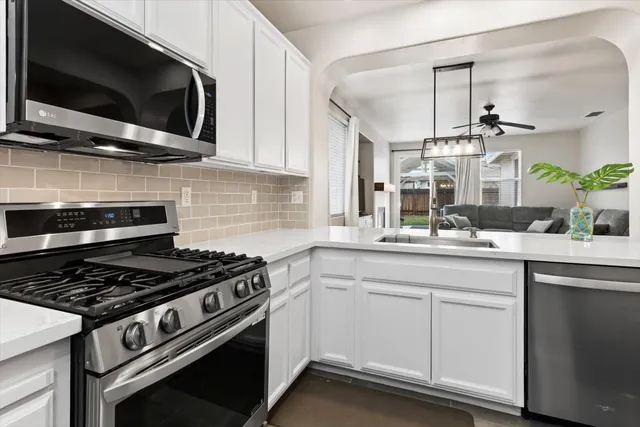 a kitchen with stainless steel appliances white cabinets and a stove top oven