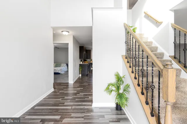 a view of an empty room with wooden floor and a kitchen