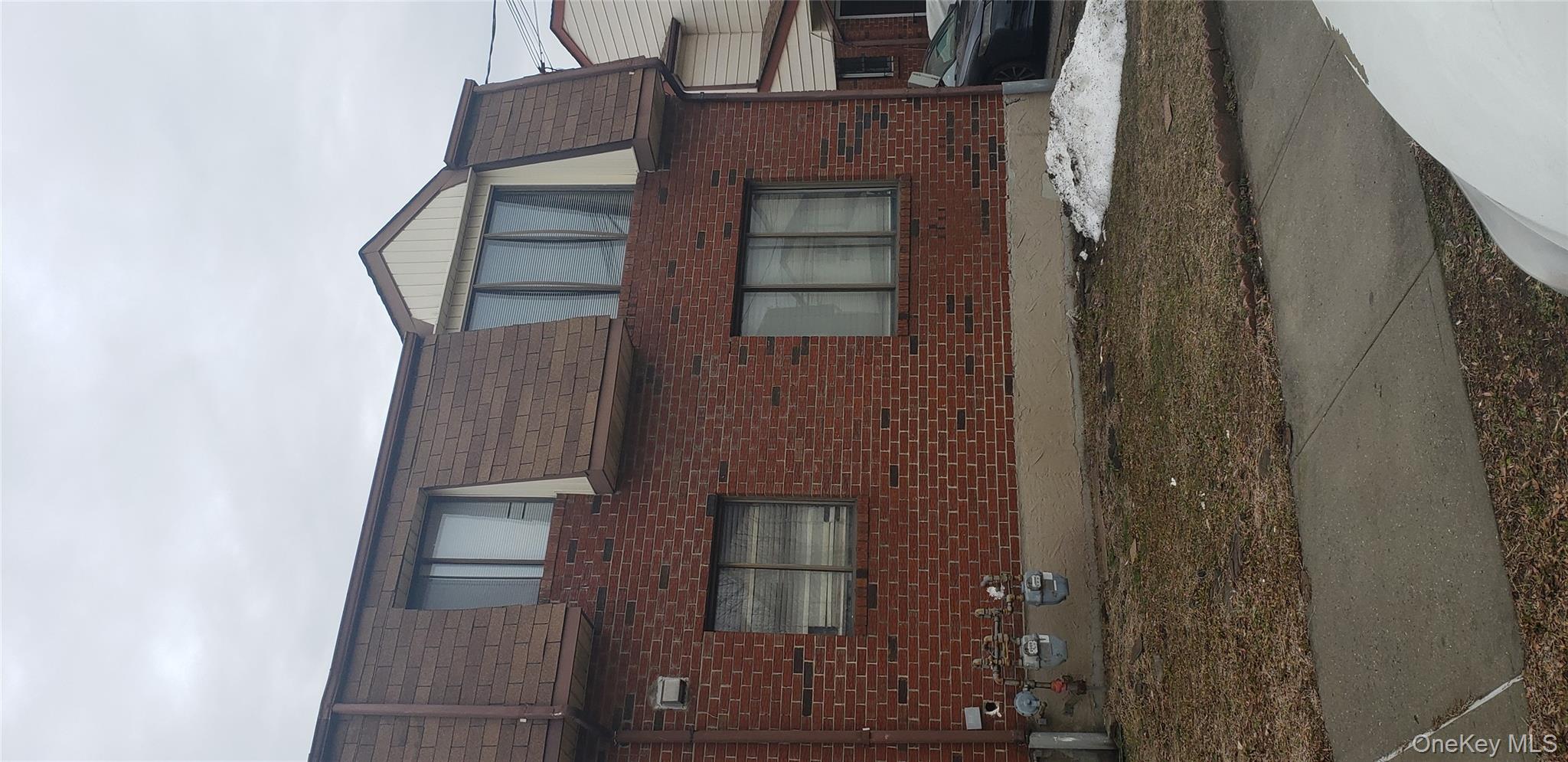 View of property exterior with mansard roof and brick siding