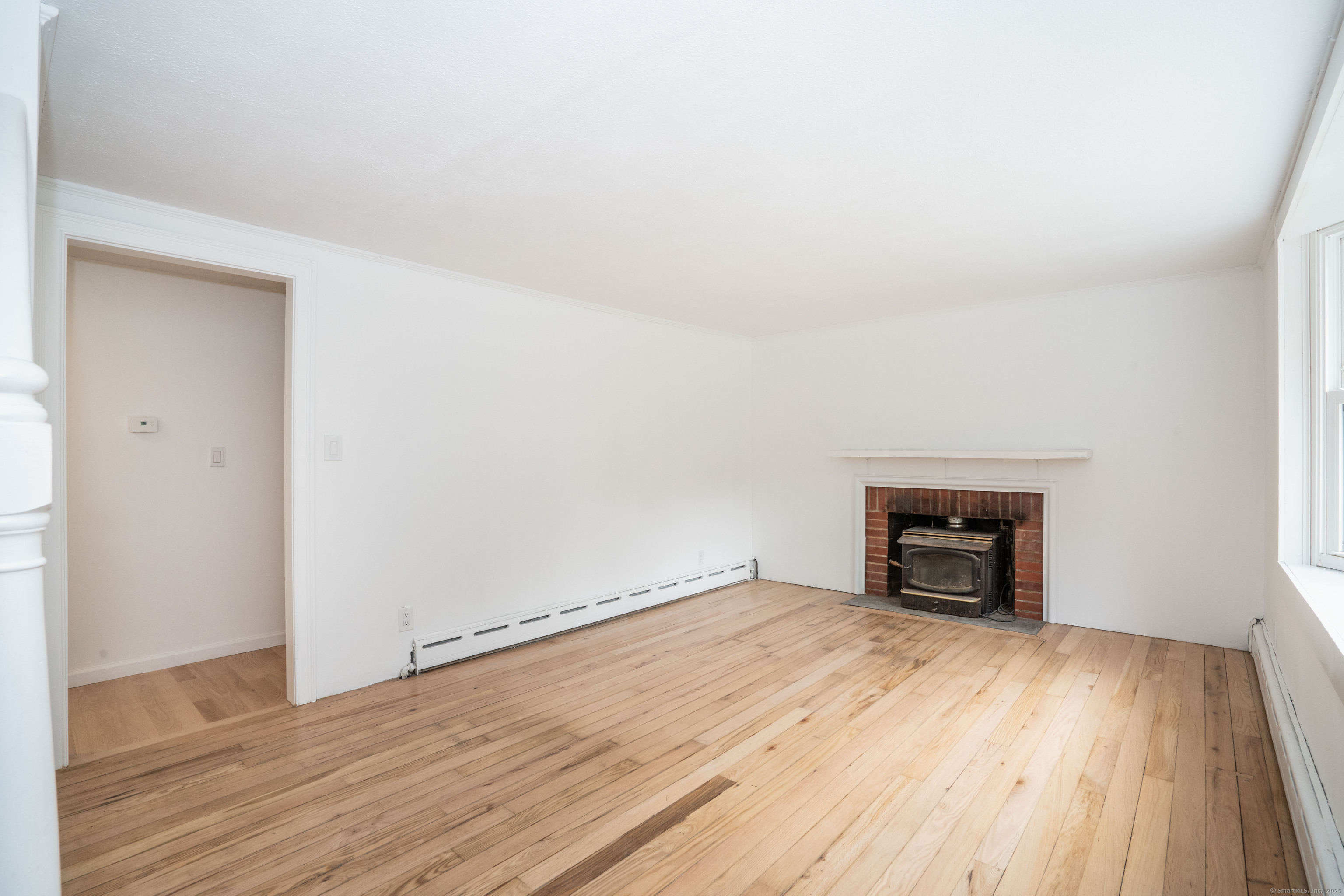 14 Main St Extension Simsbury, CT 06081 - Photo 12 of 39 an empty room with wooden floor and a fireplace