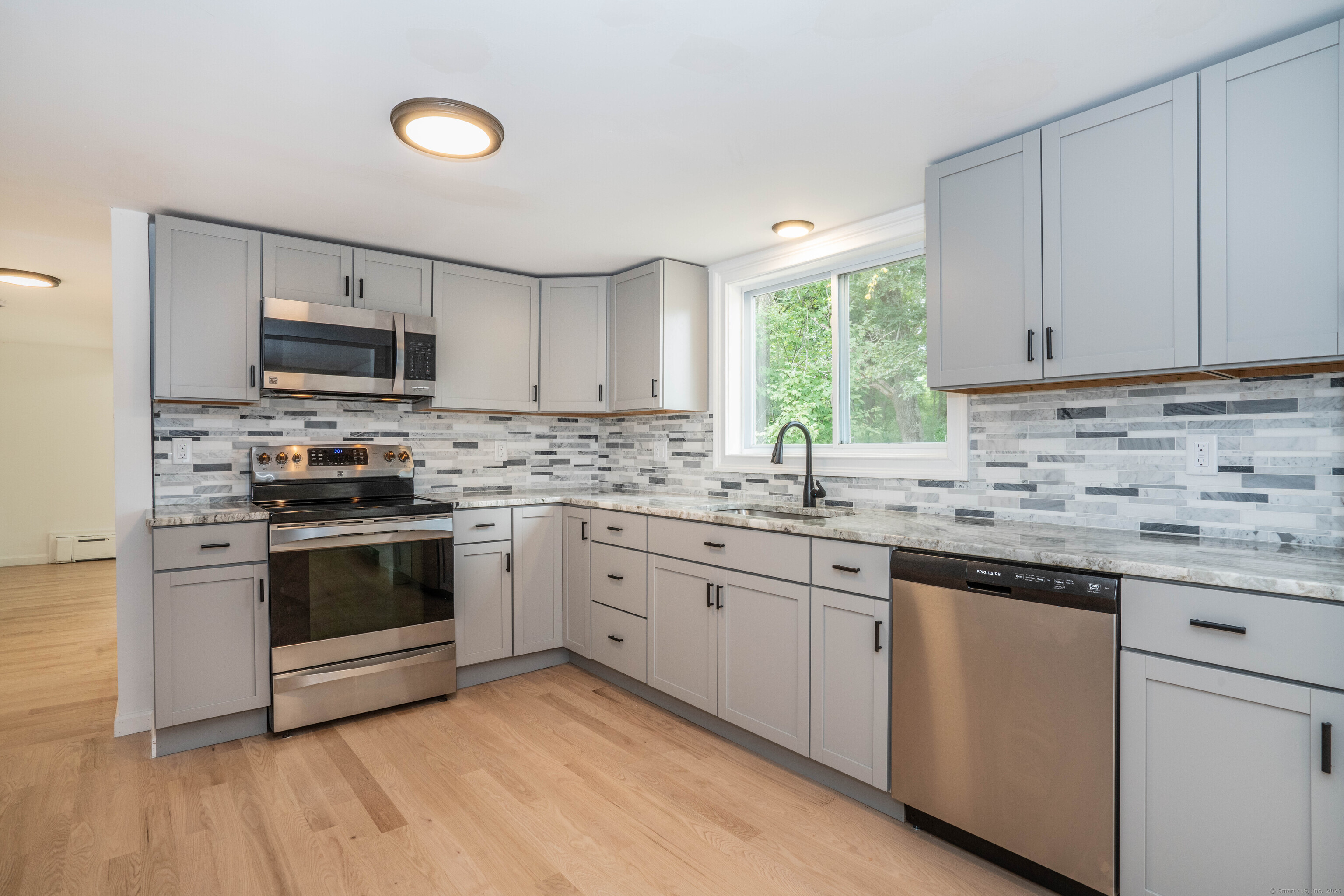 14 Main St Extension Simsbury, CT 06081 - Photo 3 of 39 a kitchen with granite countertop a stove a sink and a microwave