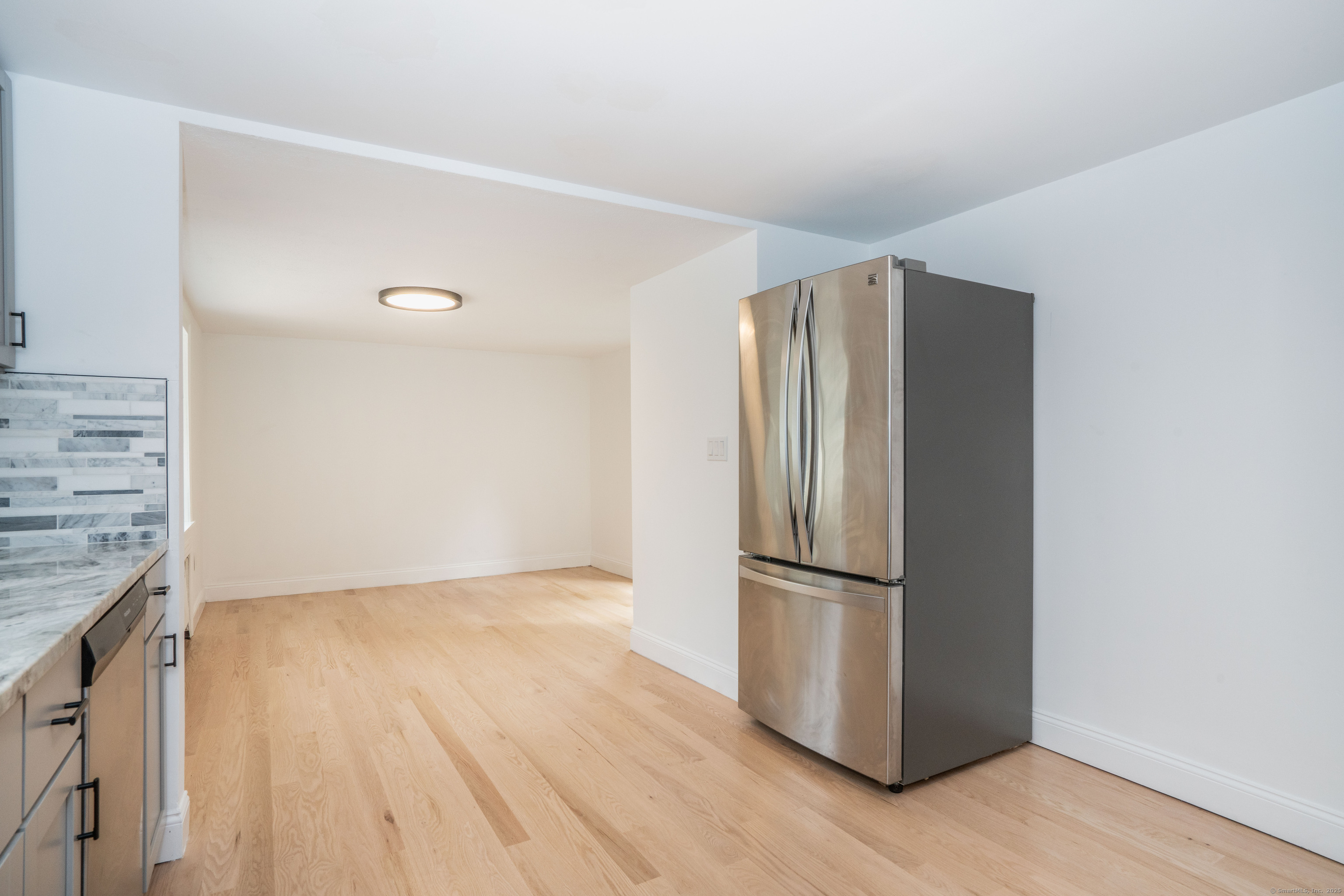 14 Main St Extension Simsbury, CT 06081 - Photo 39 of 39 a view of a refrigerator in kitchen and an empty room with wooden floor