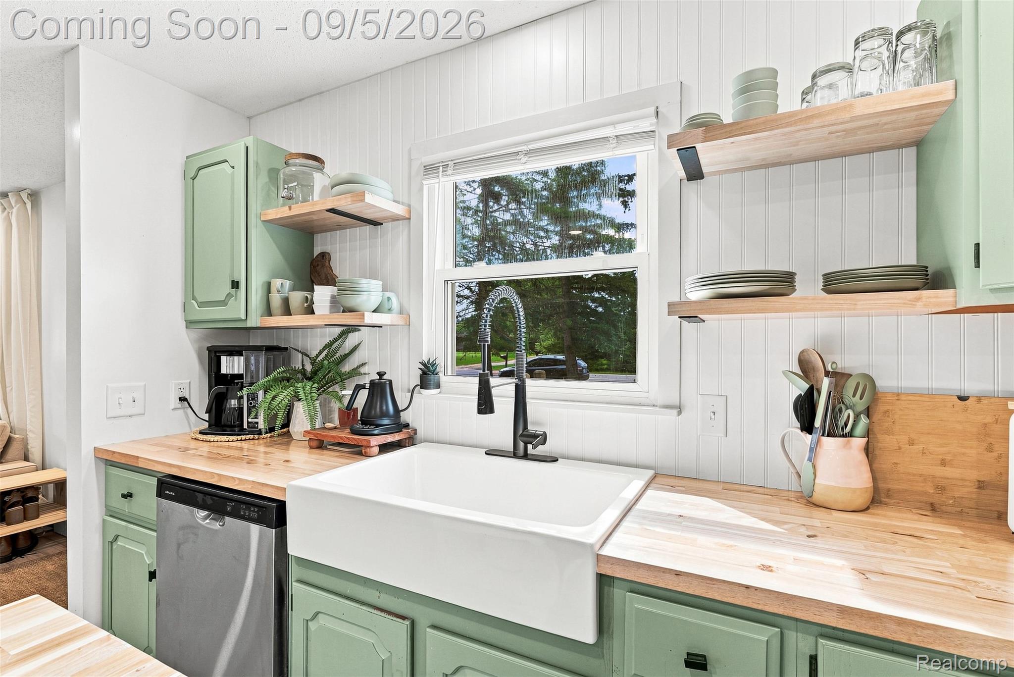 2071 East Dodge Road Clio, MI 48420 - Photo 14 of 38 White farmhouse sink with a gooseneck faucet, light wood-finish countertops, open shelving, and light green cabinetry