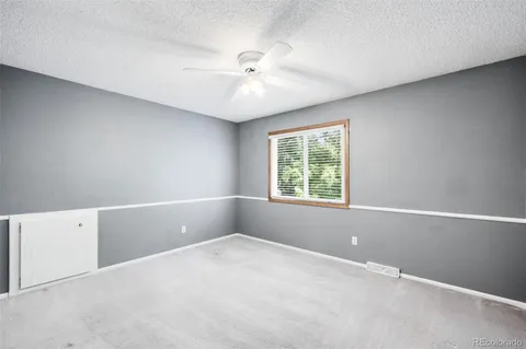 an empty room with chandelier fan and windows