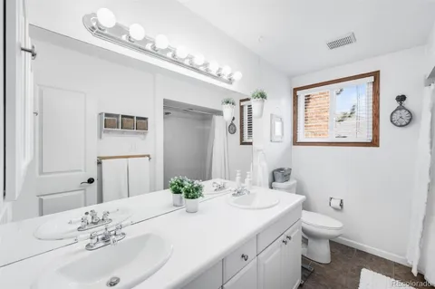 a bathroom with a granite countertop sink a toilet and a mirror