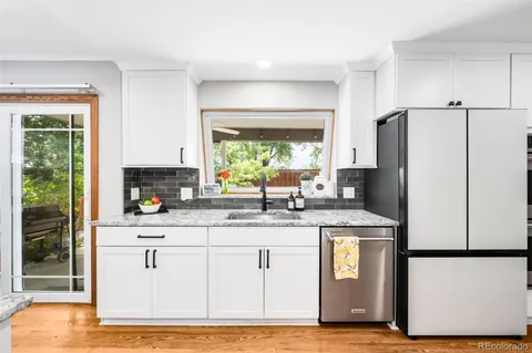 a kitchen with stainless steel appliances granite countertop a refrigerator a stove a sink and a window