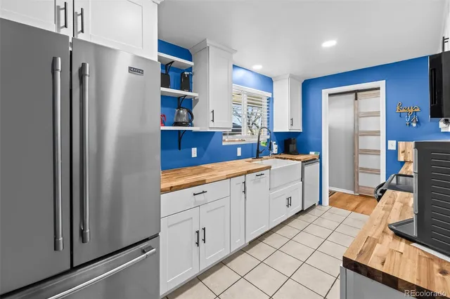 a large white kitchen with stainless steel appliances granite countertop a stove and a sink