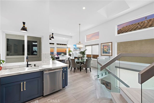 a open kitchen with stainless steel appliances granite countertop a sink dishwasher a stove and a dining table with wooden floor