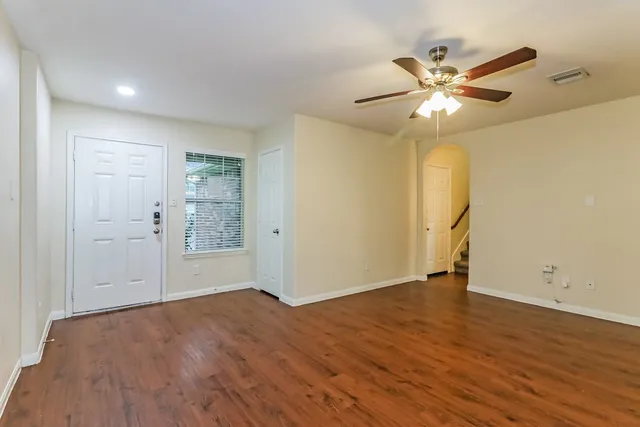 an empty room with wooden floor closet and fan chandelier