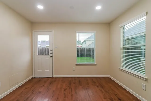 an empty room with wooden floor and windows