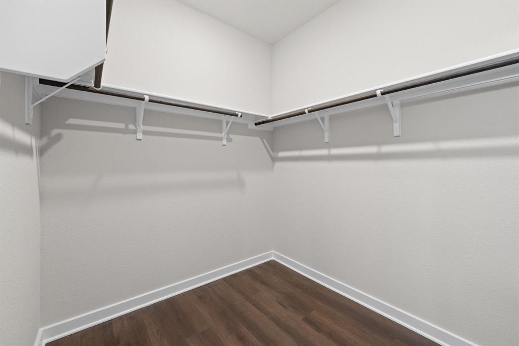 177 Sleep Hollow Jarrell, TX 76537 - Photo 18 of 24 Walk-in closet featuring wood-finish flooring, white walls, white baseboards, and built-in white shelving with hanging rods