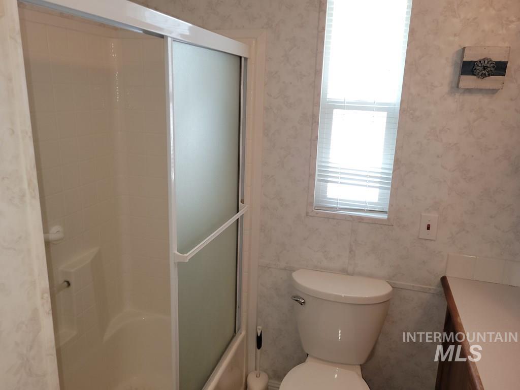 21 E Street Cascade, ID 83611 - Photo 12 of 26 Full bathroom with wallpapered walls, vanity, and shower / bath combination with glass door