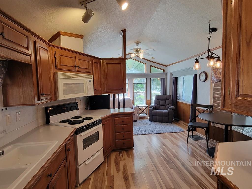21 E Street Cascade, ID 83611 - Photo 26 of 26 Kitchen with white appliances, light countertops, wood finish cabinetry, open floor plan, and light wood-type flooring