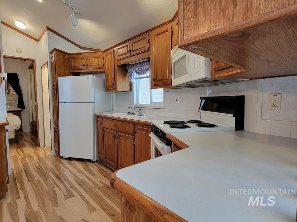 21 E Street Cascade, ID 83611 - Photo 7 of 26 Kitchen featuring light countertops, white appliances, vaulted ceiling, wood finish cabinets, and light wood finished floors
