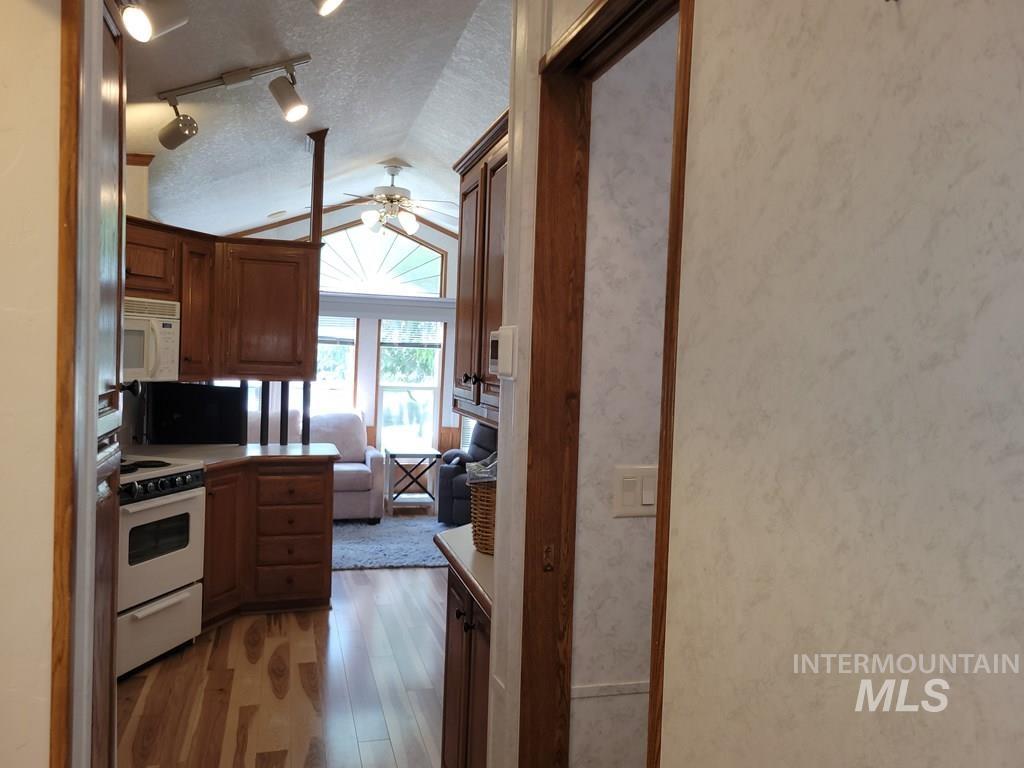 21 E Street Cascade, ID 83611 - Photo 8 of 26 Kitchen featuring a textured ceiling, white appliances, light wood-type flooring, track lighting, and ceiling fan