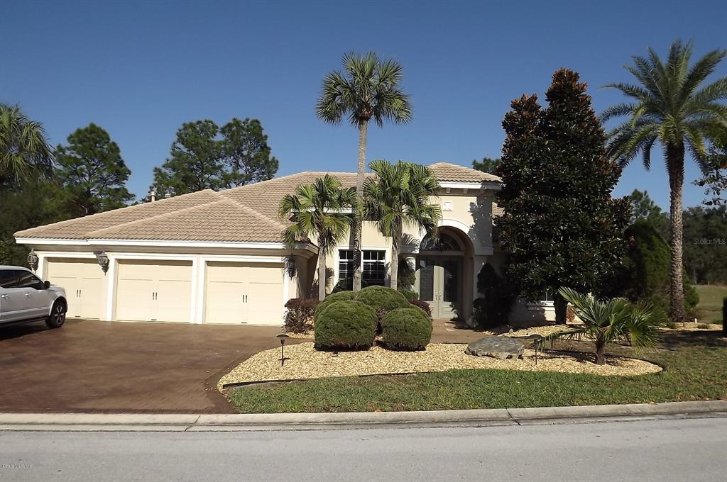 a front view of a house with garden and trees