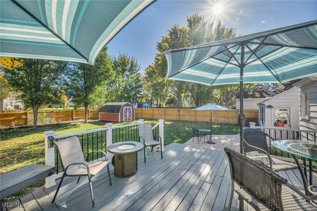 3285 Stoney Ridge Road Avon, OH 44011 - Photo 8 of 43 Wooden deck featuring a storage unit, outdoor dining space, a fenced backyard, and an outdoor fire pit