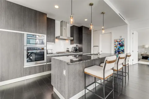 a kitchen with stainless steel appliances kitchen island granite countertop a refrigerator a sink a stove and a wooden floors