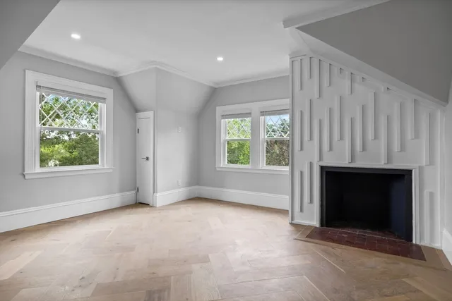 an empty room with windows and fireplace
