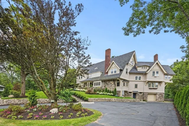 a view of a white house next to a yard with big trees