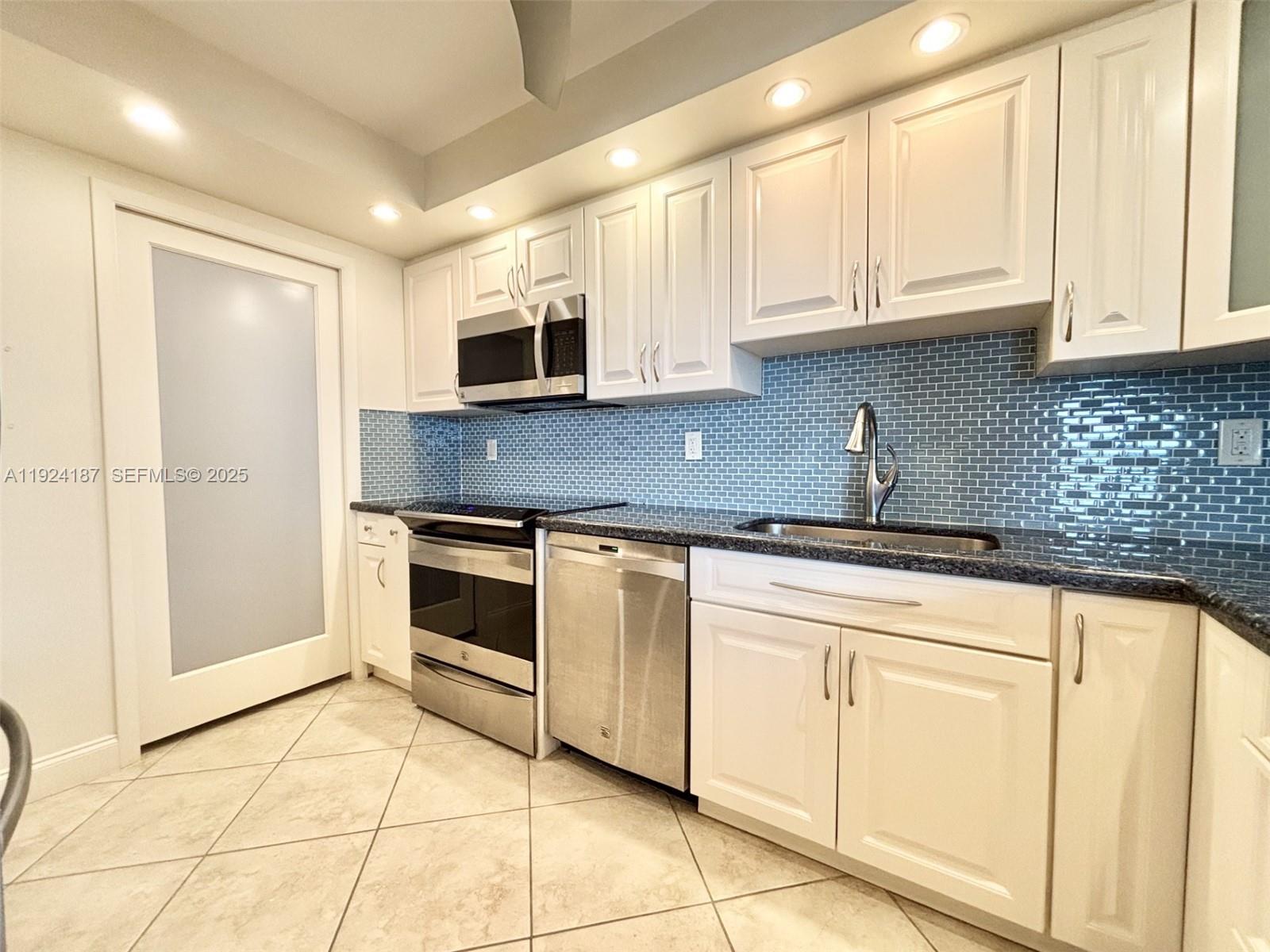 9273 Collins Avenue, Unit 705 Surfside, FL 33154 - Photo 13 of 40 a kitchen with stainless steel appliances granite countertop a sink and a stove