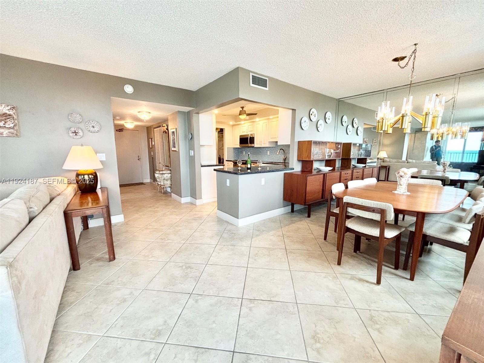 9273 Collins Avenue, Unit 705 Surfside, FL 33154 - Photo 20 of 40 a dining hall with couches a dining table and chairs with a large mirror next to a window
