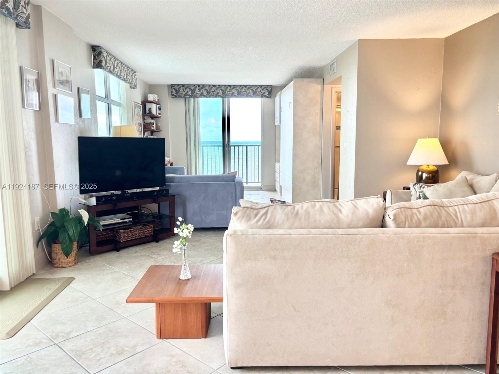 9273 Collins Avenue, Unit 705 Surfside, FL 33154 - Photo 24 of 40 a living room with furniture and a flat screen tv