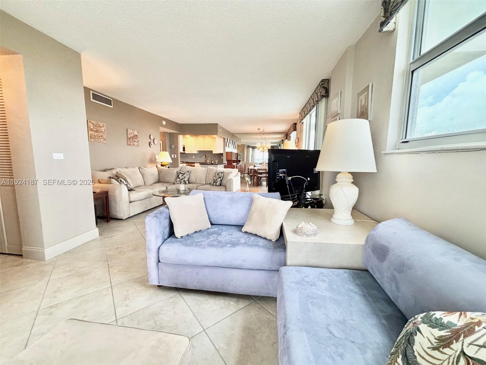 9273 Collins Avenue, Unit 705 Surfside, FL 33154 - Photo 26 of 40 a living room with furniture and a lamp