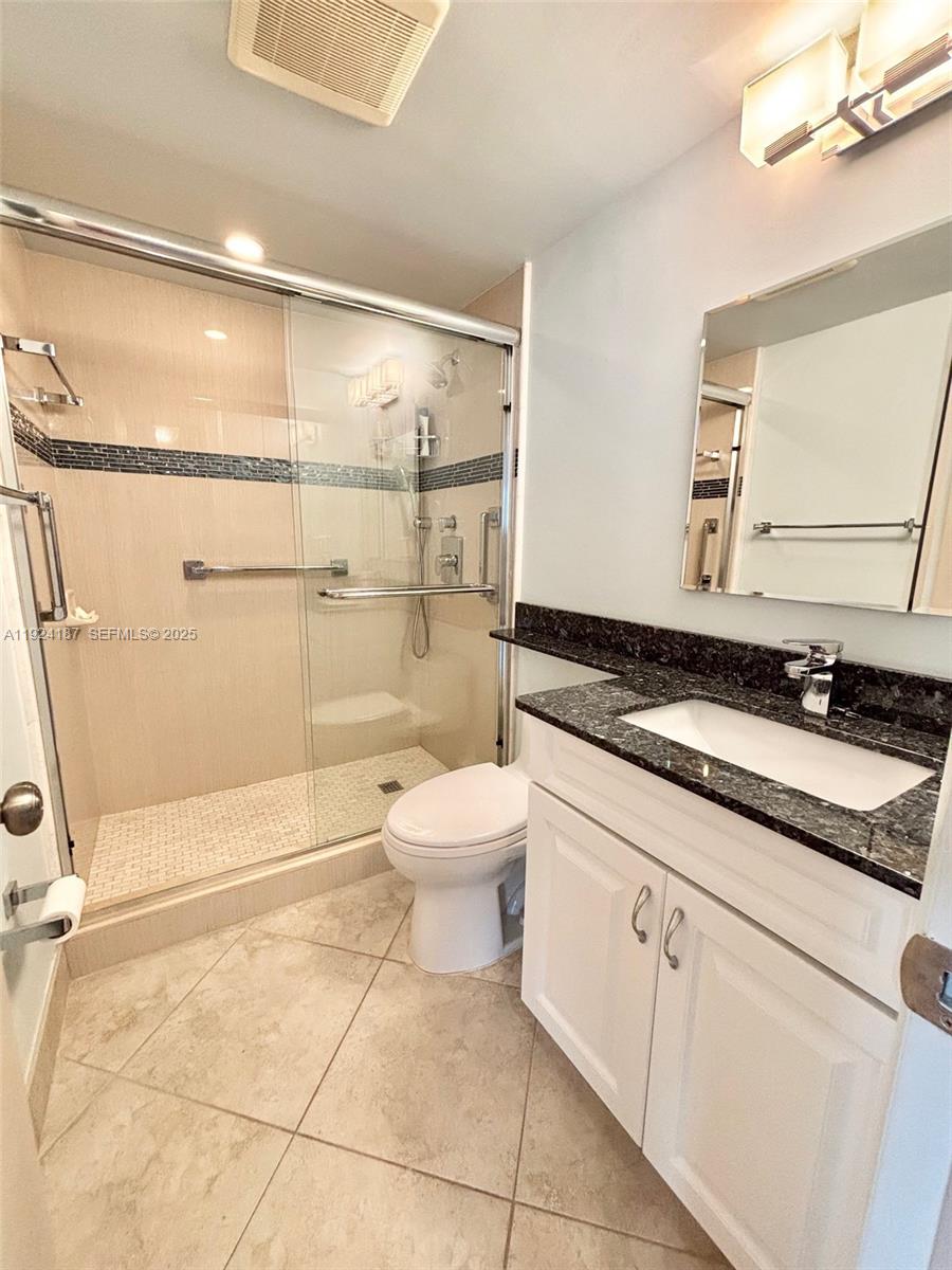 9273 Collins Avenue, Unit 705 Surfside, FL 33154 - Photo 27 of 40 a bathroom with a granite countertop sink a toilet and a shower