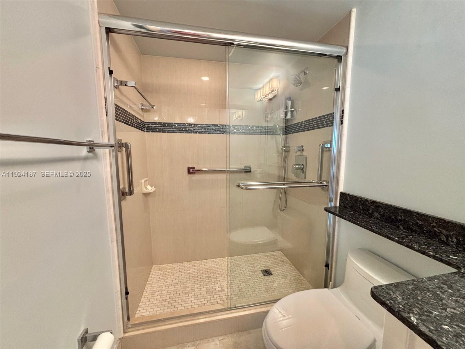 9273 Collins Avenue, Unit 705 Surfside, FL 33154 - Photo 28 of 40 a bathroom with a granite countertop shower and a toilet