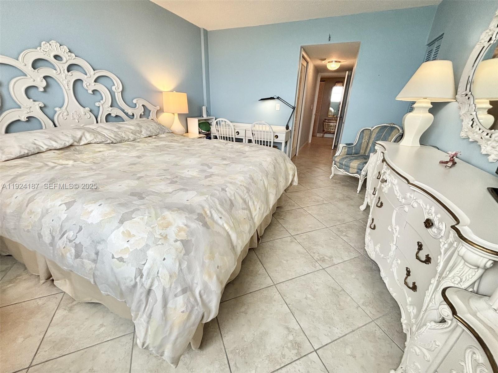 9273 Collins Avenue, Unit 705 Surfside, FL 33154 - Photo 30 of 40 a bedroom with a bed and a lamp on dresser