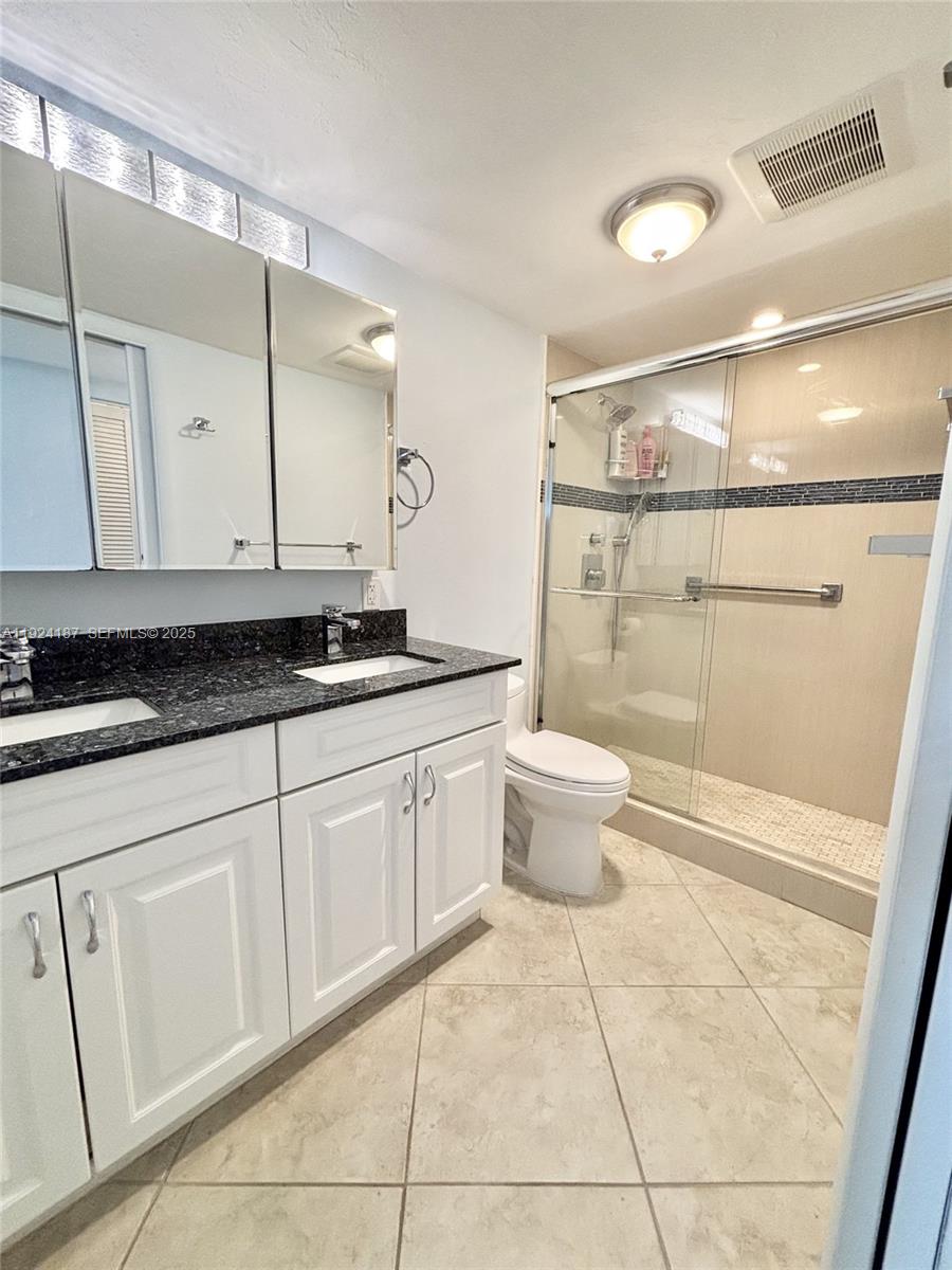 9273 Collins Avenue, Unit 705 Surfside, FL 33154 - Photo 33 of 40 a bathroom with a granite countertop sink a toilet and a mirror