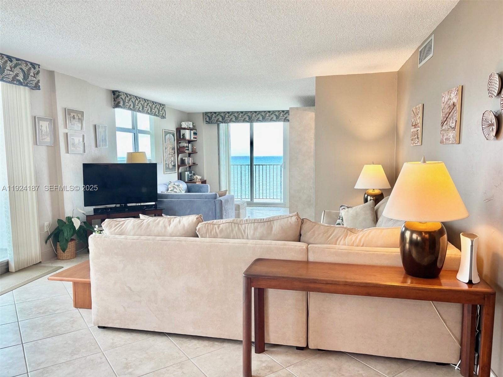 9273 Collins Avenue, Unit 705 Surfside, FL 33154 - Photo 8 of 40 a living room with furniture and a flat screen tv