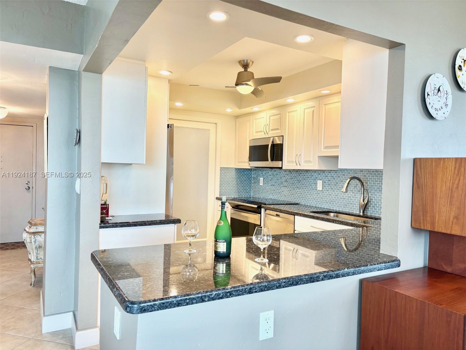 9273 Collins Avenue, Unit 705 Surfside, FL 33154 - Photo 10 of 40 a kitchen with granite countertop a sink a stove and a wooden cabinets