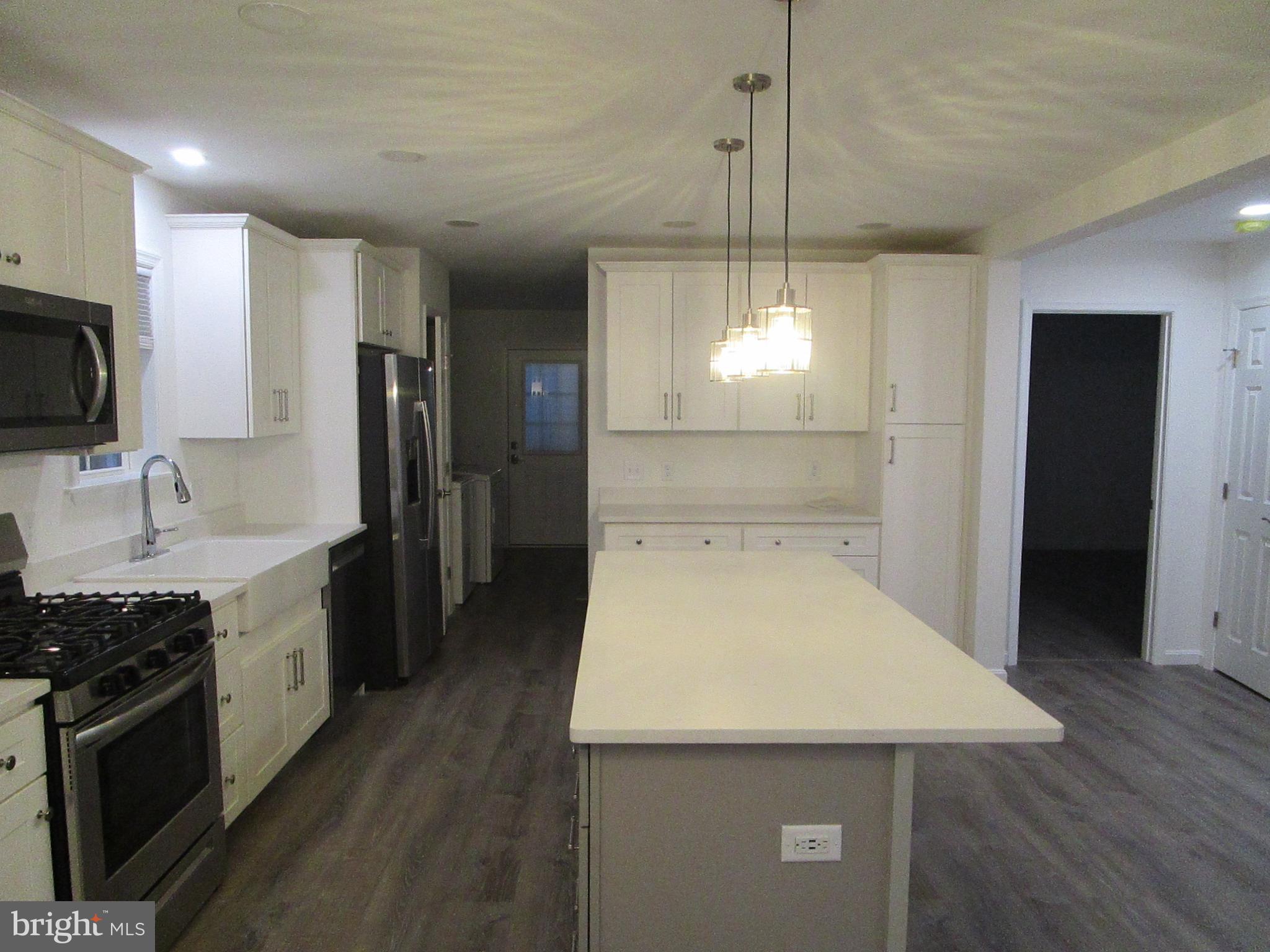 32 Tiffany Drive Rehoboth Beach, DE 19971 - Photo 13 of 43 a kitchen with stainless steel appliances wooden floor sink stove and refrigerator