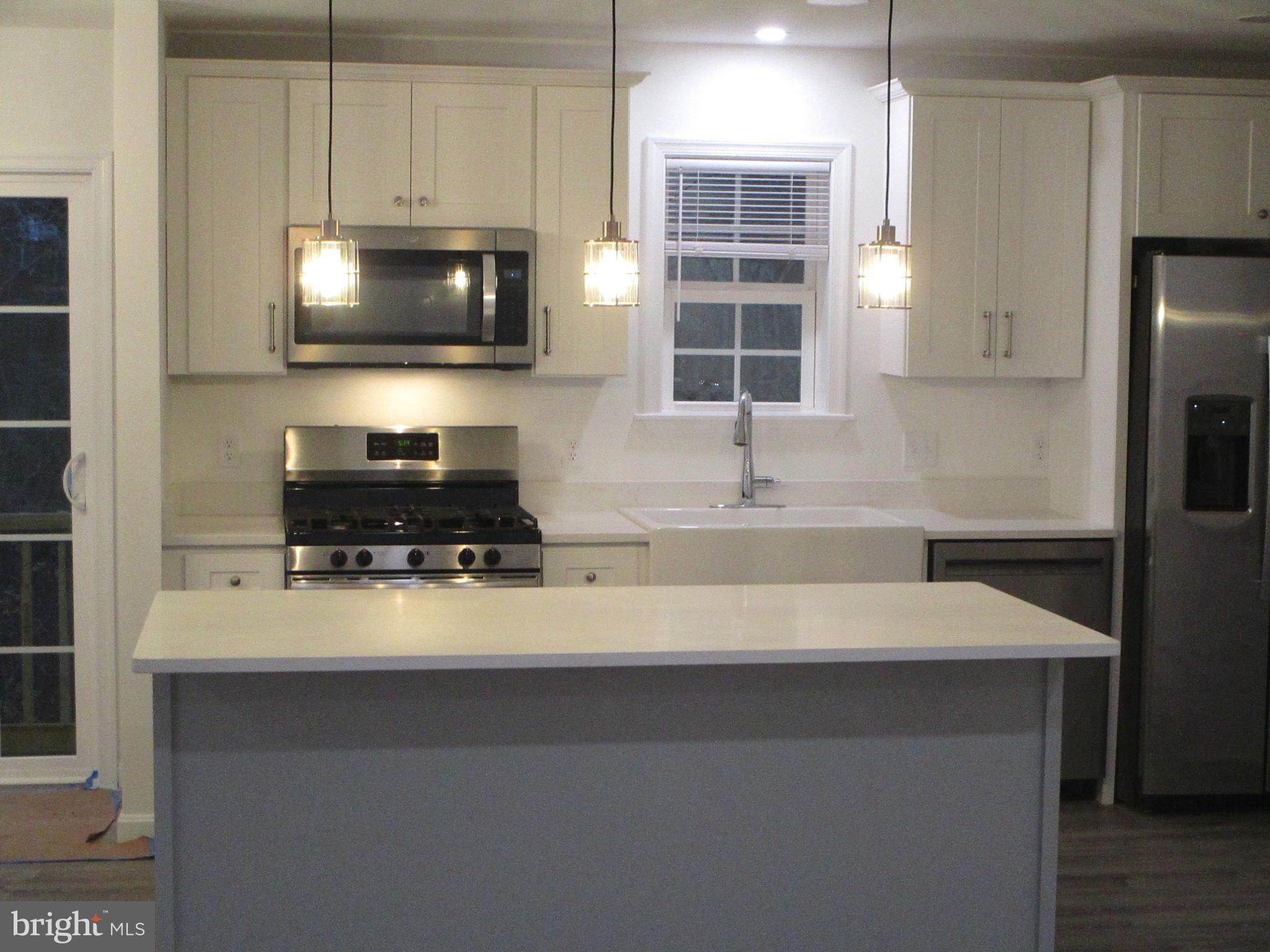 32 Tiffany Drive Rehoboth Beach, DE 19971 - Photo 16 of 43 a kitchen with stainless steel appliances a stove a sink a microwave and cabinets