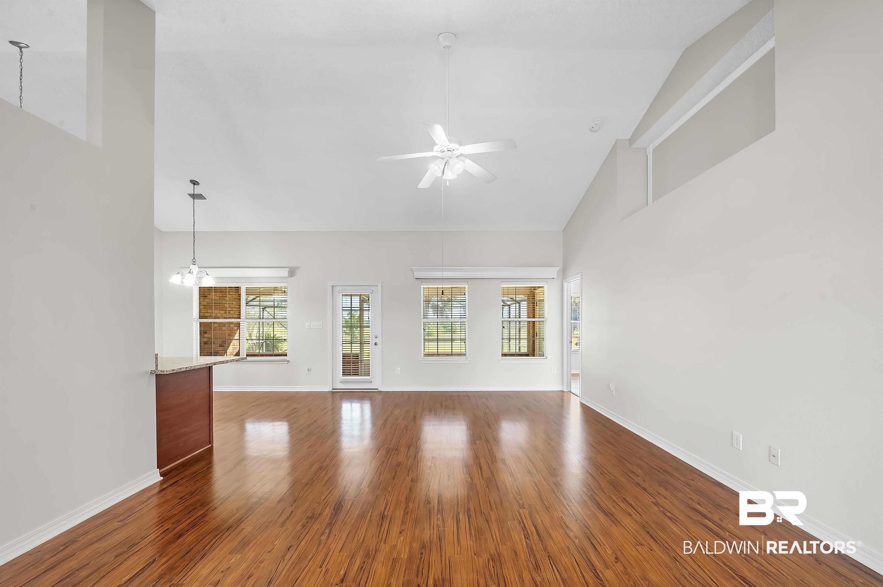 421 Collinwood Loop Foley, AL 36535 - Photo 18 of 62 Unfurnished living room with hardwood / wood-style flooring, high vaulted ceiling, and ceiling fan with notable chandelier