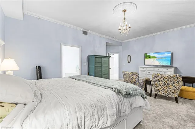 a spacious bedroom with a bed and a chandelier